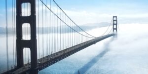 The Golden Gate Bridge stretches across the water as traffic travels across the suspension bridge in a foggy setting, supported by advanced asset management and infrastructure.