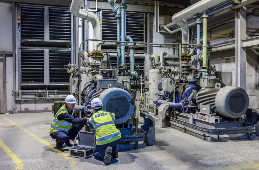 Two ERIKS technicians perform field service management, inspecting a "CONDENSER AIR EXTRACTION PUMP 10-PP-020" and "NASH" machinery with a tool kit in a factory. "LIVE" box.