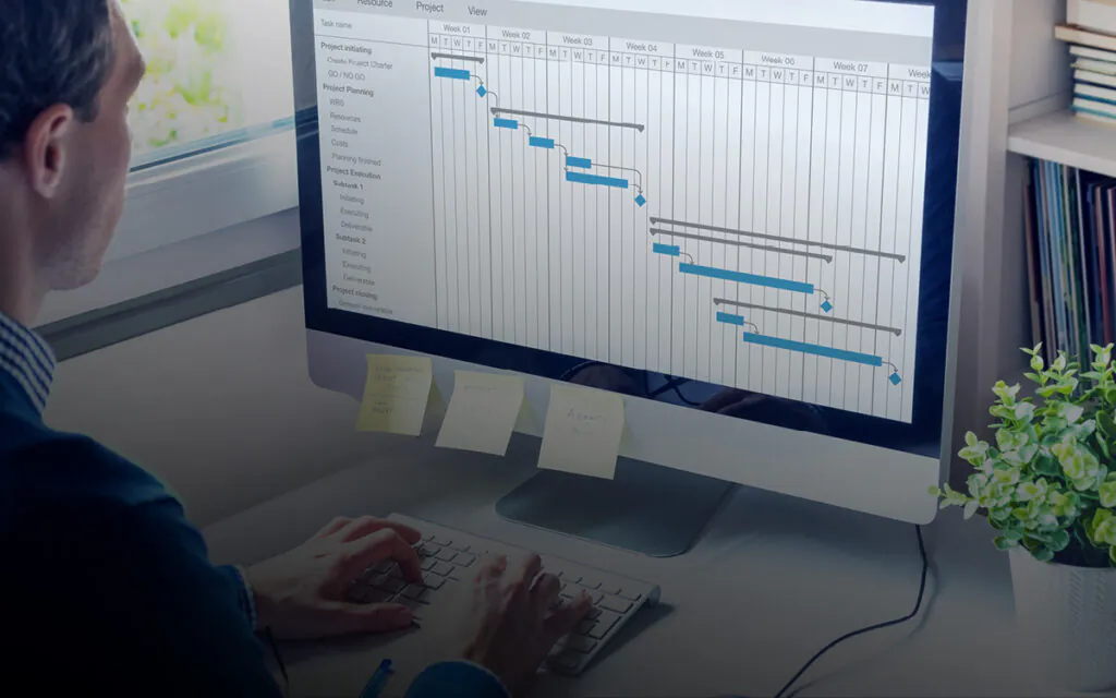 Een persoon werkt op een computer aan een gedetailleerd projectplan, waarbij SAP FSM-oplossingen helpen bij het efficiënt beheren van werkzaamheden in een kantooromgeving. Tekst op het scherm en post-its: Task name, Week 01, Week 02, Week 03, Week 04, Week 05, Week 06, Week 07, Week 08, Project initiating, Create Project Charter, GO/NO GO, Project Planning, WBS, Resources, Schedule, Costs, Planning finished, Project Execution, Subtask 1, Initiating, Executing, Deliverable, Subtask 2, Initiating, Executing, Deliverable, Project closing, General deliverable, SEND MONTHLY REPORT BEFORE 02/03 CALL ROBERT, MEETINGS MONDAY 15:30, ANSWER Anna.