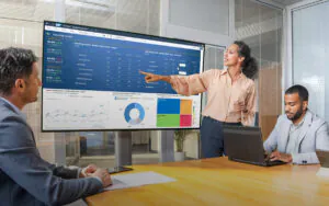 Een zakenvrouw wijst op een groot scherm met financiële grafieken ter ondersteuning van SAP technology, terwijl twee collega’s toekijken in een moderne vergaderruimte. Tekst op het scherm: < SAP | Stories | Business Review 5130 - < File - Edit - Tools - Display - Publish Data - Operating Income Q3 Ratios Actual 69.9% (+0.4) Gross Margin % (Actual - Current Plan) 11.1% (+0.1) Operating Margin % (Actual - Current Plan) 58.9% (+0.3) Operating Margin % (Actual - Current Plan) 2021 Ratios Actual 69.0% (+0.1) Gross Margin % (Actual - Current Plan) 8.5% (+0.0) Operating Margin % (Actual - Current Plan) Operating Income - BestRun Bikes Corp. - Actual 2021 Net Revenue Cost Of Goods Sold Gross Margin Total Personnel Expenses Other Operating Expenses Total Operating Expenses Operating Income Q1 (2021) 108.2 72.3 35.9 26.2 6.9 34.2 9.1 Q2 (2021) 25.3 7.1 18.2 8.9 8.0 17.2 1.8 Q3 (2021) 42.7 14.2 28.5 10.0 13.3 23.3 2.7 Q4 (2021) 35.2 11.8 23.4 11.9 12.5 23.9 4.2 Operating Income - BestRun Bikes Corp. - Q3 (2021) Net Revenue Cost Of Goods Sold Gross Margin Operating Income Actual 108.2 72.3 35.9 9.1 Current Plan 11.5 15.0 6.5 0.8 % of Current Sales & Rental Revenue - BestRun Bikes Corp. - Actual in USD | 3 Years | 2 Filters | 1 Explorer View Sales Revenue • Rental Revenue Net Revenue per Company - Q3 (2021) - Actual in USD | 3 Years | 1 Explorer View BestRun Bikes Europe BestRun Bikes USA BestRun Bikes UK BestRun Bikes Operating Expenses - BestRun Bikes Corp. - Q3 (2021) - Actual in USD | 3 Years | 1 Explorer View EU Cost Centers US Cost Centers UK Cost Centers BestRun Cost Centers