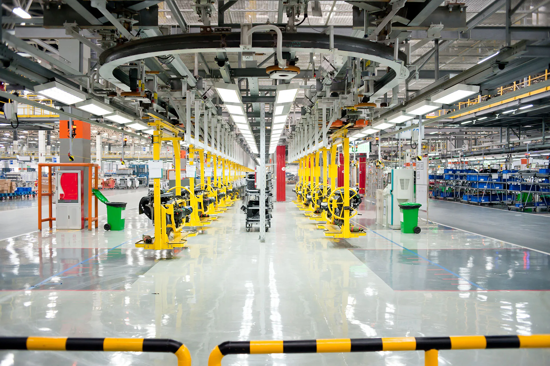 Geelgekleurde assemblagemachines bewegen langs een railsysteem door een moderne fabriekshal, wat essentieel is voor efficiënt field service management en het stroomlijnen van complexe industriële onderhoudsprocessen.