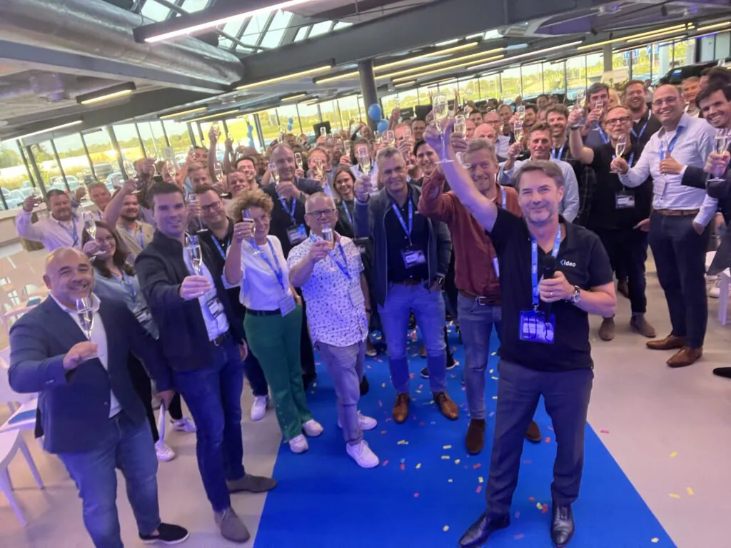 Een grote groep professionals heft het glas tijdens een feestelijke bijeenkomst in een modern pand, waarbij ze successen vieren die aansluiten bij innovatieve oplossingen zoals SAP FSM.