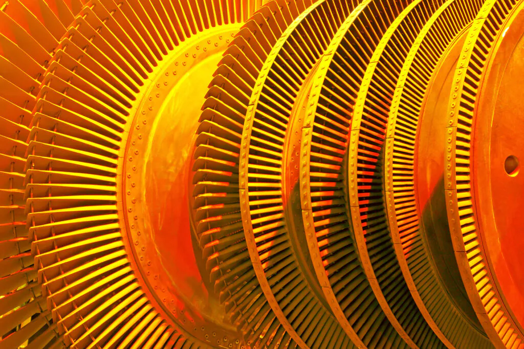Een industriële turbine met talrijke metalen schoepen draait rond in een machinekamer, wat essentieel is voor effectief asset management binnen grote energiecentrales.
