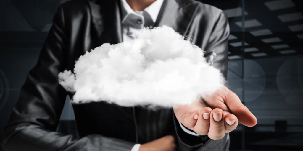 Een zakelijk geklede persoon houdt een witte, zwevende wolk vast in een handpalm tegen een donkere achtergrond, wat innovatieve oplossingen symboliseert zoals die binnen SAP FSM worden toegepast.